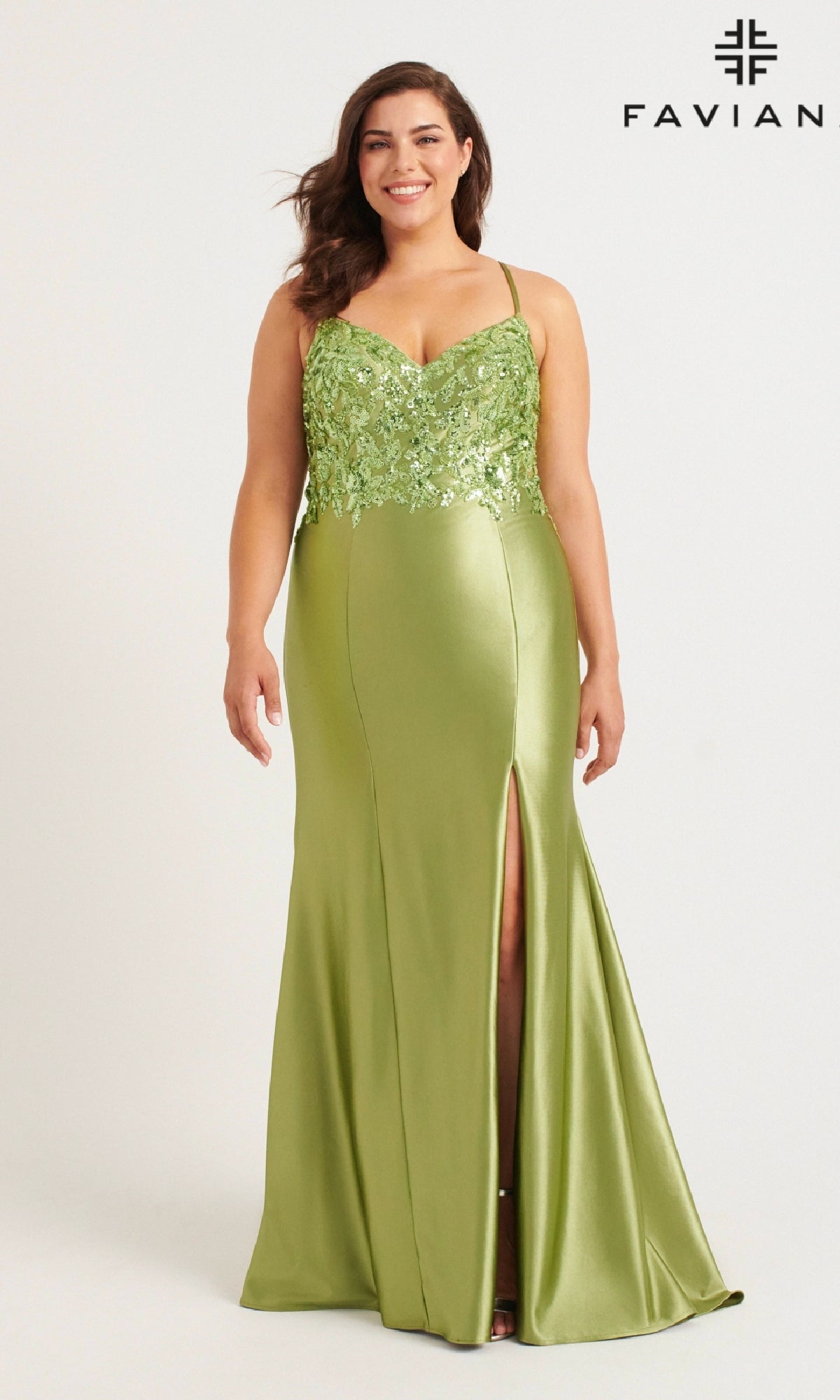A woman wears the Faviana 9563 long plus-size prom dress in light green satin, featuring spaghetti straps, a sequin appliqué bodice, and a front slit. The background is plain white with the FAVIANA logo in the top right.